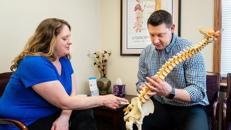 Dr. Wunderlich explaining spine anatomy to a patient using a spine model